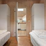 Two beds in a room with wood walls and door to kitchen.