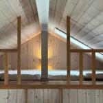 Upper sleeping area with wooden railing and sloped ceiling.