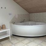 Shower with bathtub and showerhead. Wooden ceiling and tiled floor.