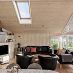 Living area with wooden walls, sofa, seating group, and TV. Large windows and skylight.