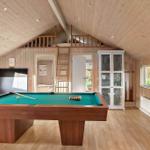 Room with pool table, wood walls, and loft area.