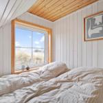 Schlafzimmer mit Fenster und Bett unter Holzdecke.