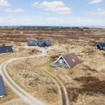 Aerial view of several cabins on a grassy landscape with winding dirt paths.