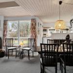 Dining room with table, chairs, and wood stove. Kitchen in background.
