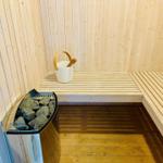 Sauna with wooden bench, stone heater, and bucket with ladle.