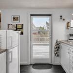 Kitchen with white cabinetry, refrigerator, and door to balcony.