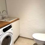 Badezimmer mit Waschmaschine, Waschbecken und Toilette