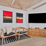 Wohnzimmer mit TV, zwei Sesseln und Holzmöbeln.