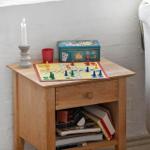 Holzsideboard mit Brettspiel, Kerze und Bücherregal neben Sessel