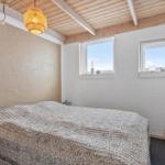 Schlafzimmer mit Bett, zwei Fenstern und Holzdecke.