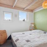 Schlafzimmer mit Bett, zwei Fenstern und grüner Wand.