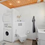 Badezimmer mit Waschmaschine, Trockner, WC und Waschtisch.