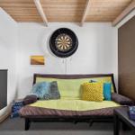 Raum mit Sofa, Dartboard und Bücherregal an der Wand.