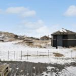Schneebedeckter Strandbereich mit Holzterrasse und mehreren Häusern im Hintergrund.