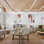 Wohnzimmer mit Sofa, Sessel und runden Tisch. Holzdecke und Fenster mit Blick.