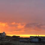 Sonnenuntergang über Häusern und Grasland