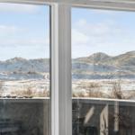 Durch das Fenster blickt man auf sandige Dünen mit trockenem Gras.