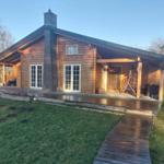 Wooden house with terrace, grill, and swing in the garden.