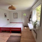Bedroom with red bed, wooden floor, and window with plant.
