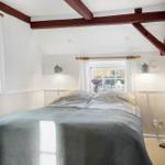 Schlafzimmer mit Bett, Fenstern und Holzbalken an der Decke.