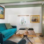 Ein Wohnzimmer mit grünem Sofa, Holztisch und Wandbildern.