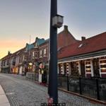 Straßenszene mit historischen Gebäuden und einem Restaurant im Abendlicht.