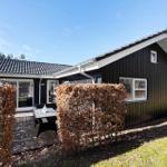 Black wooden house with terrace and garden. White windows and roof gutter.