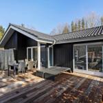 House with terrace, table, chairs, and loungers. Black facade, wooden deck, and glass front.