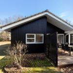 Black house with terrace and garden. Table and chairs on the veranda.