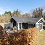Modern cabin with terrace and seating, surrounded by hedges and trees.