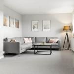 Ein Wohnzimmer mit grauem Sofa, Tisch und Wandbildern.