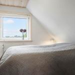 Schlafzimmer mit Bett, Fenster und Lampe.