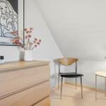 Schlafzimmer mit Schrank, Stuhl und Nachttisch unter schräger Decke.