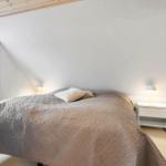 Schlafzimmer mit Bett, Nachttisch und Fenster. Holzdecke und helles Licht.
