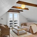 Wohnzimmer mit Sofa, Sessel und Tisch unter Holzbalken.