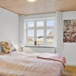 Schlafzimmer mit Bett, Fenster und Holzdecke.
