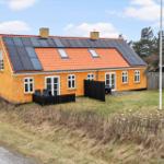 Ein gelbes Haus mit Solarpanelen auf dem Dach und einem Garten.