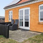 Orange Haus mit Terrasse, zwei Stühlen und Solaranlage auf Dach.