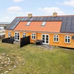Ein gelbes Haus mit Solaranlage und Garten. Terrasse mit Tisch und Stühlen.