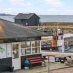 Café-Kiosk am Hafen mit Bootsanlegestelle und Blick aufs Wasser.
