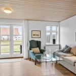 Wohnzimmer mit Sofa, Sessel und Glas-Tisch. Holzdecke und große Fenster.