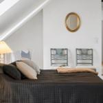 Schlafzimmer mit Dachschrägen, Bett, zwei Stühlen und Spiegel an der Wand.