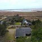 Haus mit Terrasse, umgeben von Bäumen und Blick auf Fluss und Strand.