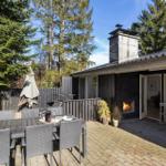 Terrace with seating area, grill space, and wooden house with fireplace and windows.