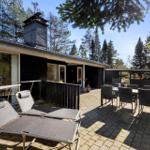 Modern wooden cabin with terrace, lounge chairs, and table in the woods.