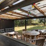 Patio with seating, table, chairs, and string lights under roof.