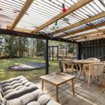Terrace with seating, table, trampoline, and wood cladding.