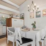 Dining room with table, chairs, and kitchen area. Wall decor and chandelier.