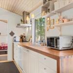 Kitchen with wooden countertop, microwave, and view into bedroom
