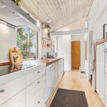 Kitchen with wooden floor, white cabinets, and wooden tools. Window view of forest.